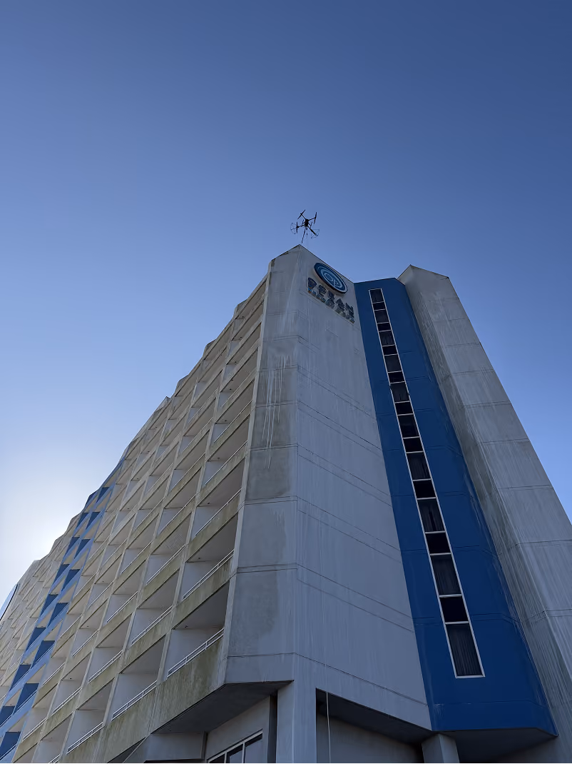 Modern high-rise building viewed from below with abstract geometric mural and blue sky with clouds.