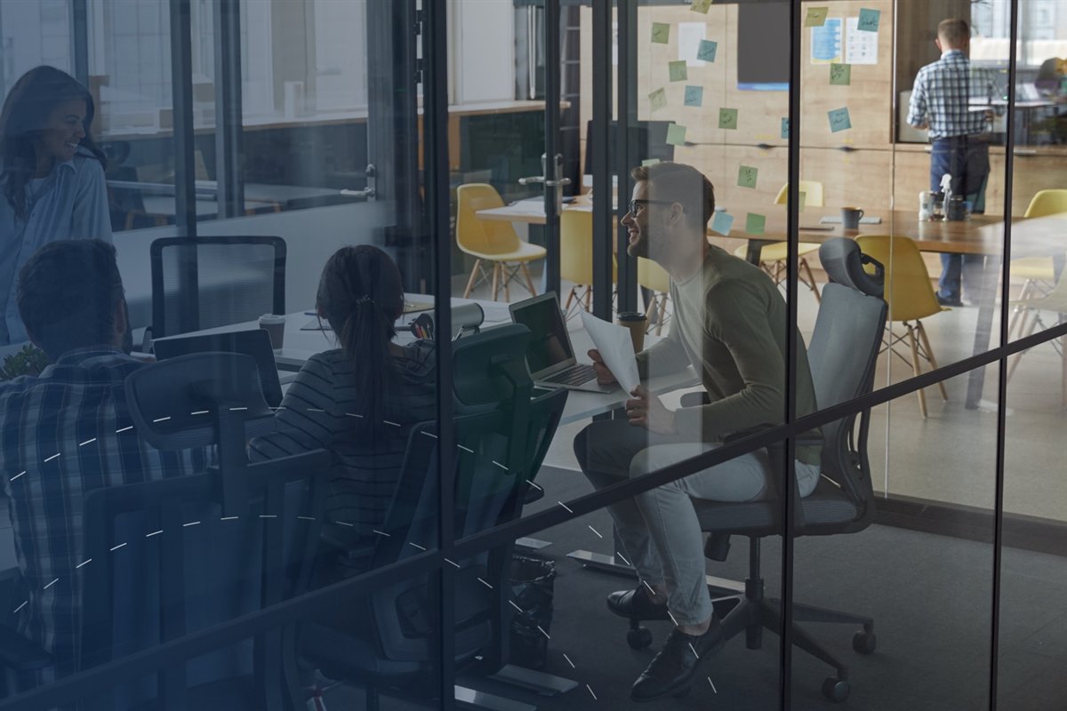 Equipo de desarrollo trabajando en una sala de reuniones vidriada