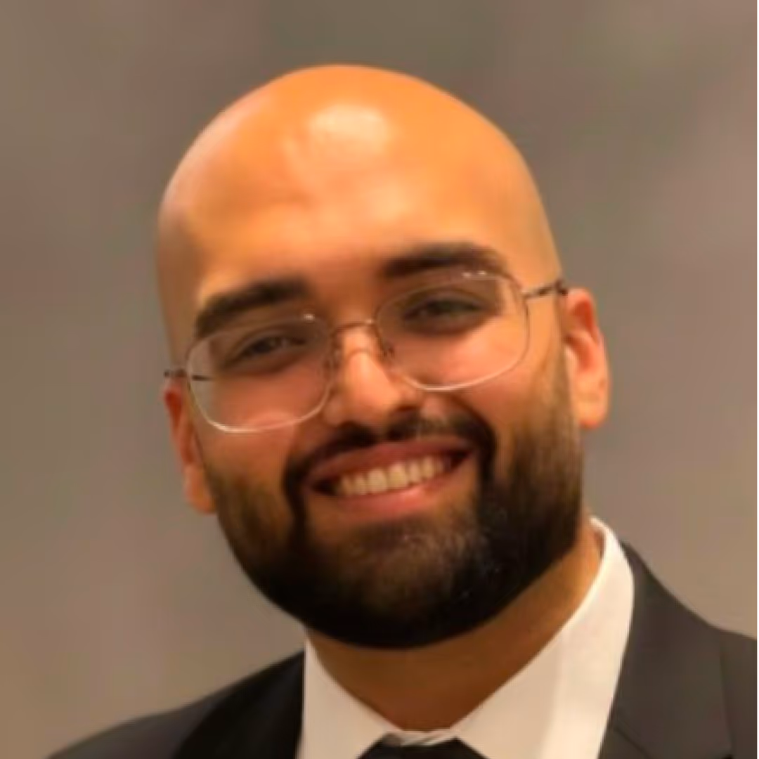 Smiling bald man with glasses and a beard wearing a black suit and white shirt.