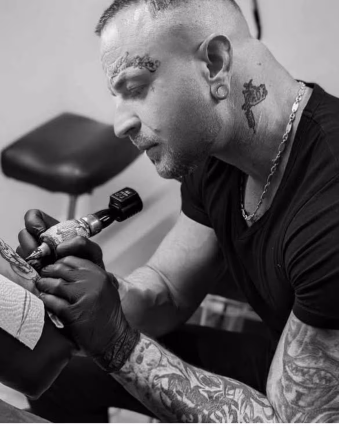 Tätowierer bei der Arbeit im Tnt-Tattoo Studio in Herford, muskulöser Mann, konzentriert beim Tätowieren im Tattoo Studio in Herford Innenstadt.