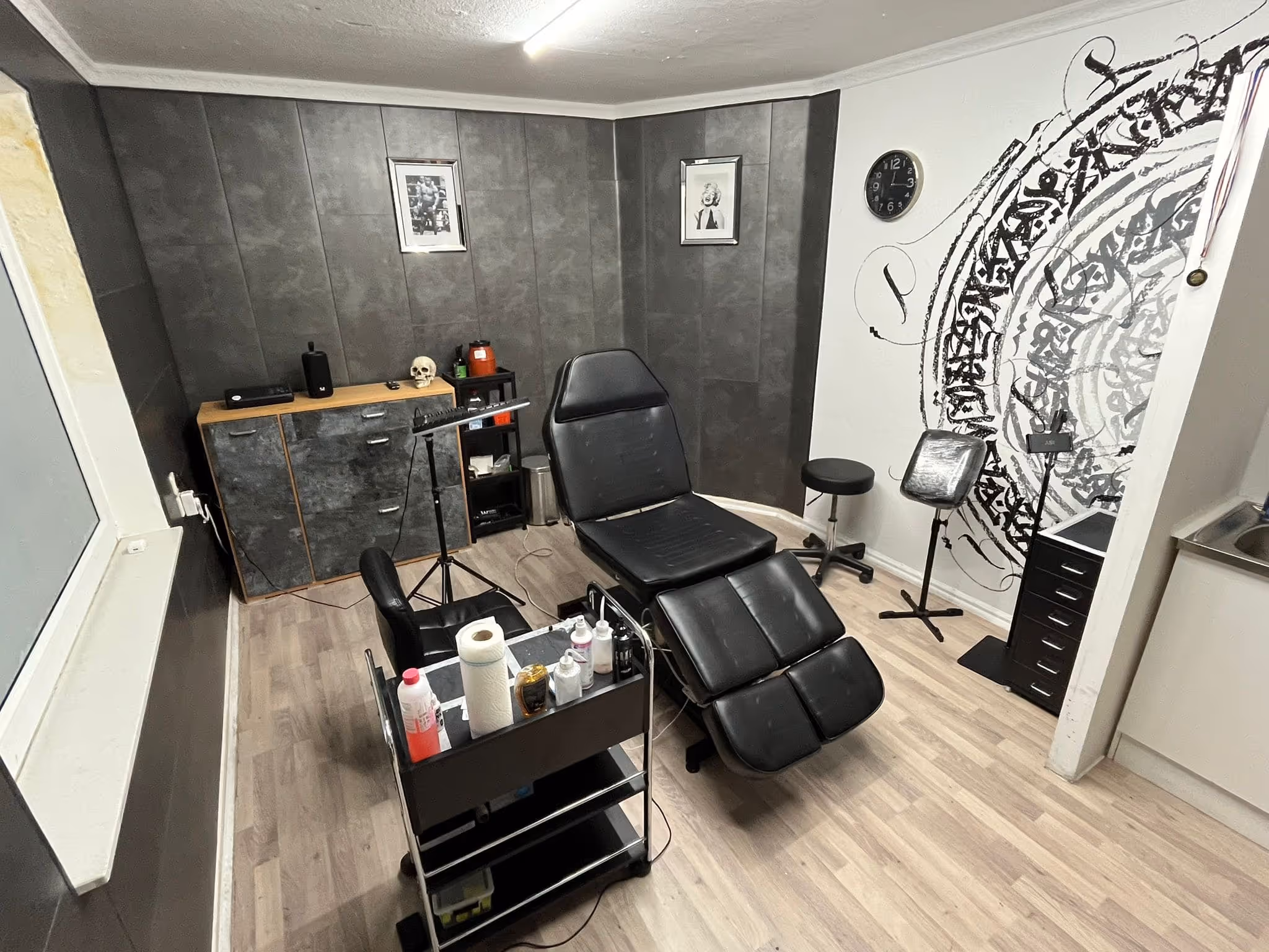 Arbeitsbereich im Tattoo Studio Tnt-Tattoo in Herford, Schwarzer Tattoo-Stuhl, Materialien, Bilder an der Wand – In der Innenstadt Herford.