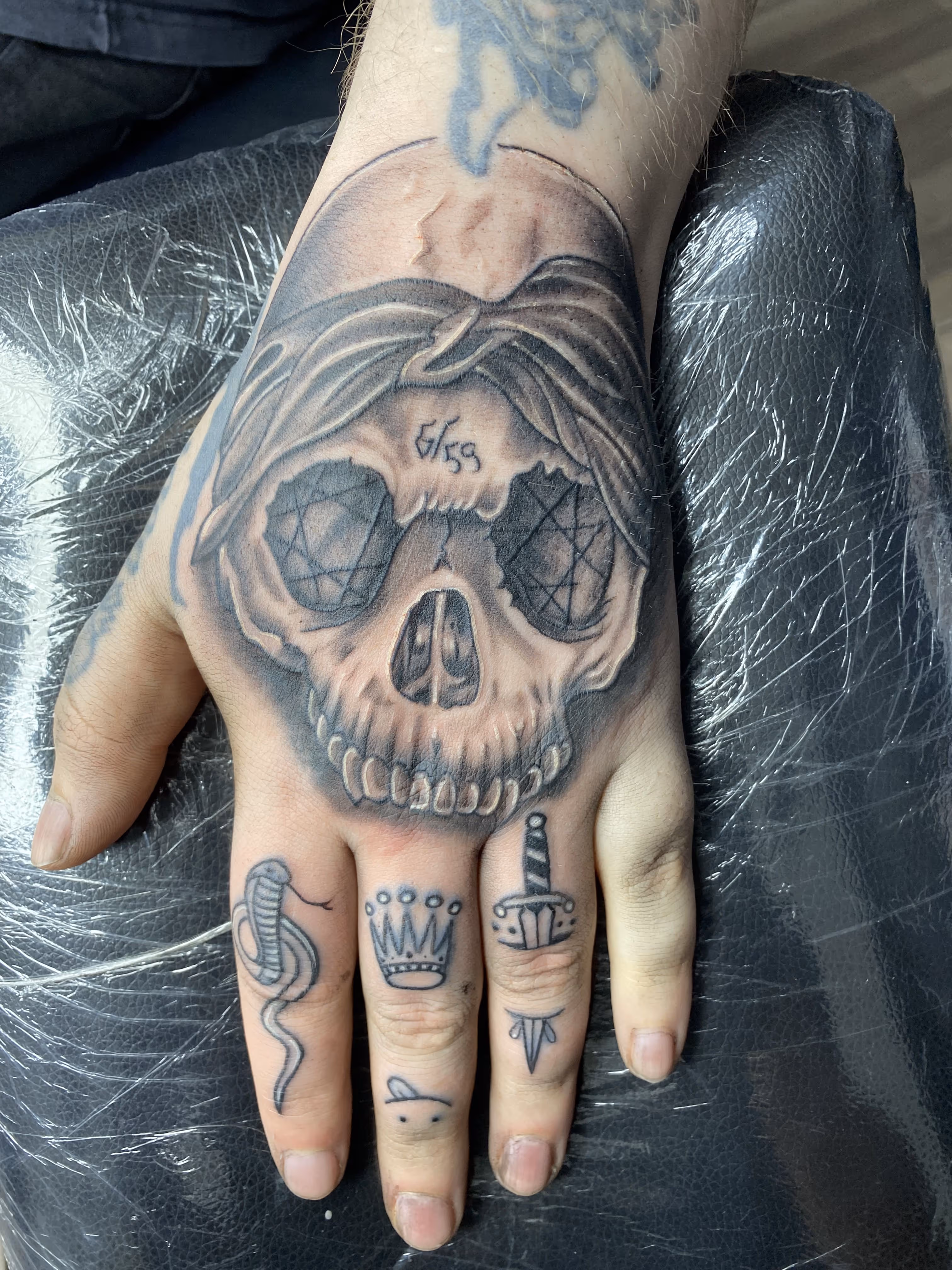 Hand-Tattoo mit Totenkopf und tätowierten Fingern im Tnt-Tattoo Studio in Herford am Gänsemarkt.