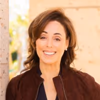 Man wearing a red tuxedo jacket with black lapels, a white shirt, and a red bow tie, standing indoors with a neutral expression.