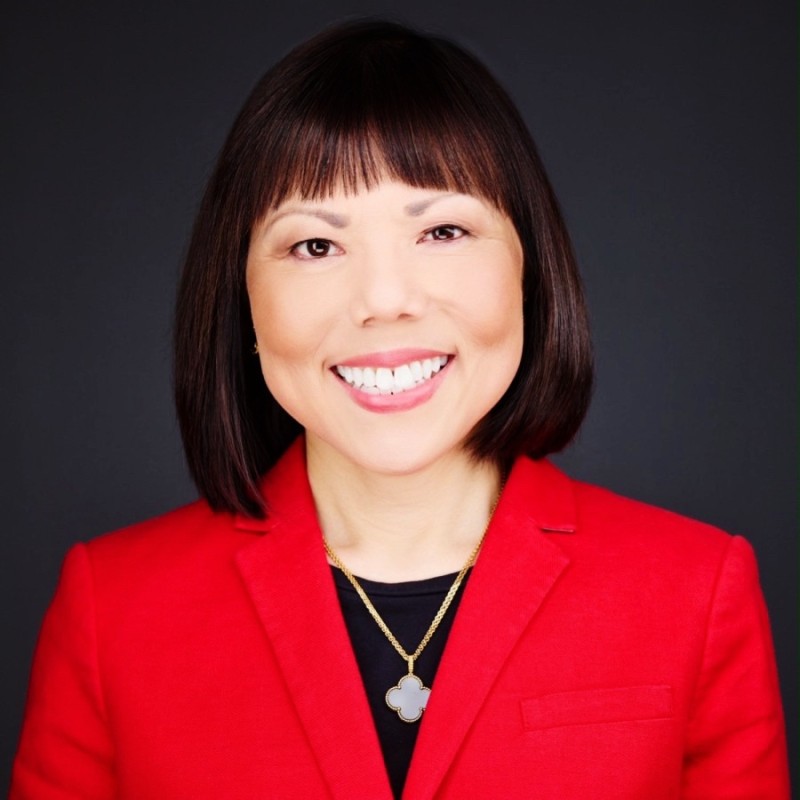 Man wearing a red tuxedo jacket with black lapels, a white shirt, and a red bow tie, standing indoors with a neutral expression.