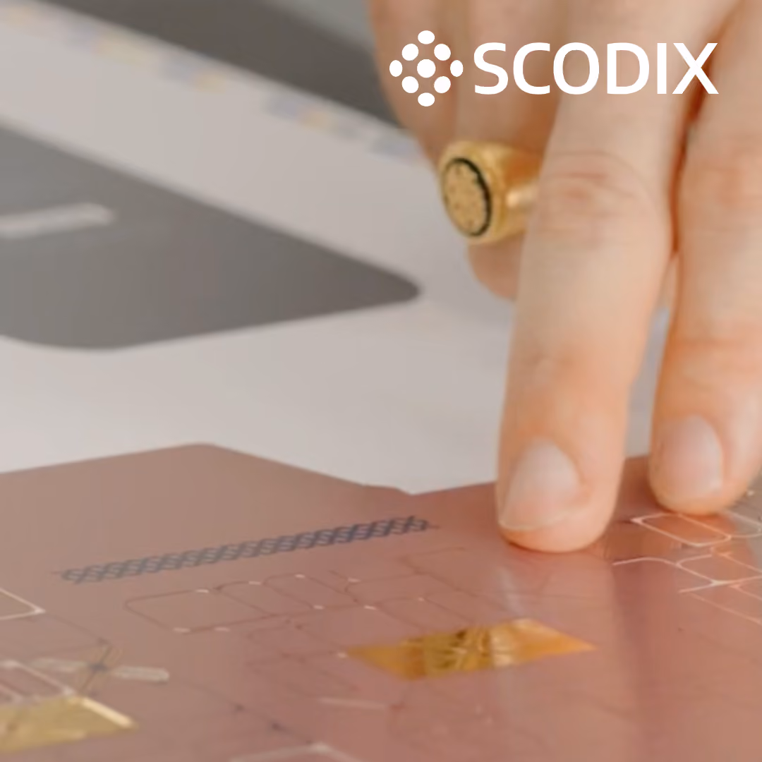 Close-up of a hand touching a textured printed sheet with the Scodix logo above.
