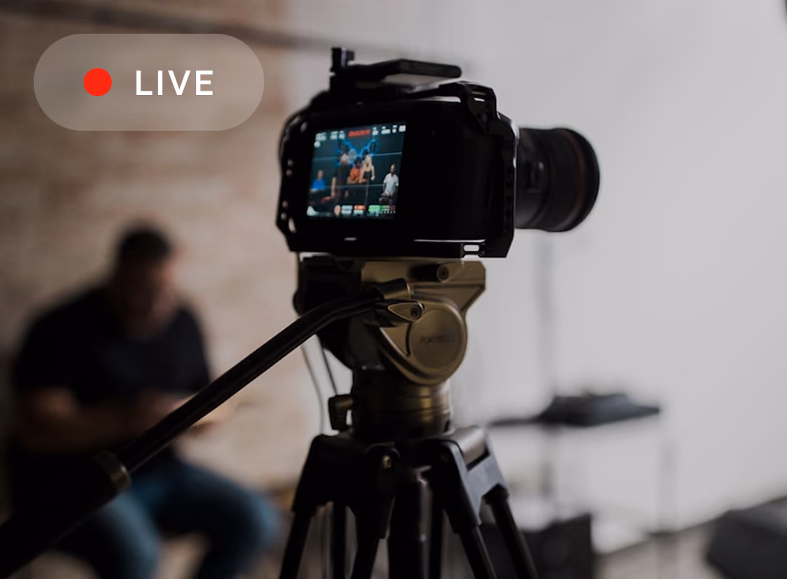 Camera on tripod recording a live video with people shown on the camera screen.