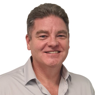 Smiling middle-aged man with short brown hair wearing a light gray button-up shirt.