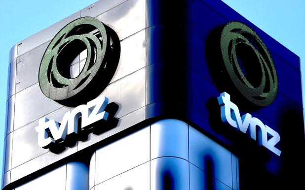 Building corner with TVNZ logo featuring a circular emblem and text on a reflective metallic surface.