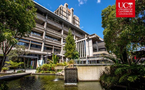 University of Canterbury campus showing modern buildings, trees, and a pond with a small waterfall.