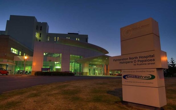 View of Palmerston North Hospital entrance at dusk with an illuminated smokefree sign.
