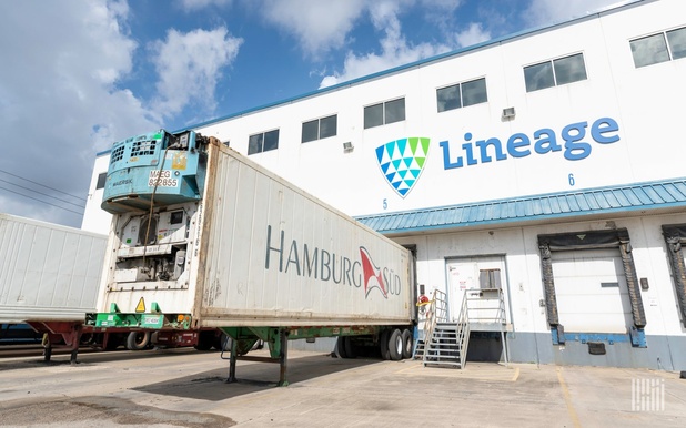 Hamburg Sud freight container trailer parked outside a Lineage warehouse under blue sky.