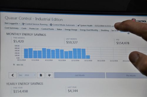 Screen of Quasar Control showing monthly and yearly energy savings with bar graph and a hand pointing at the screen.