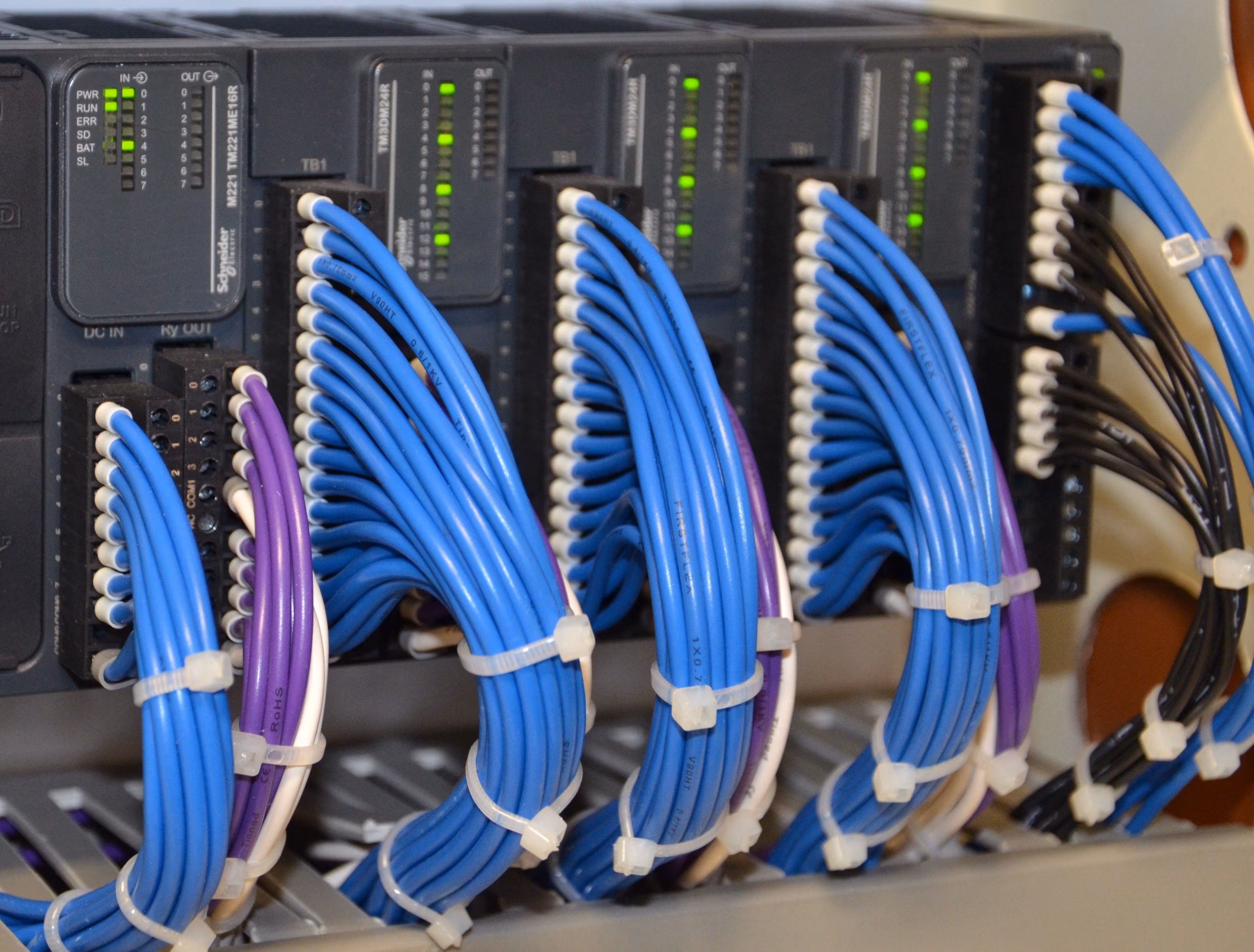 Bundles of blue, purple, black, and white wires organized and tied inside a control panel.
