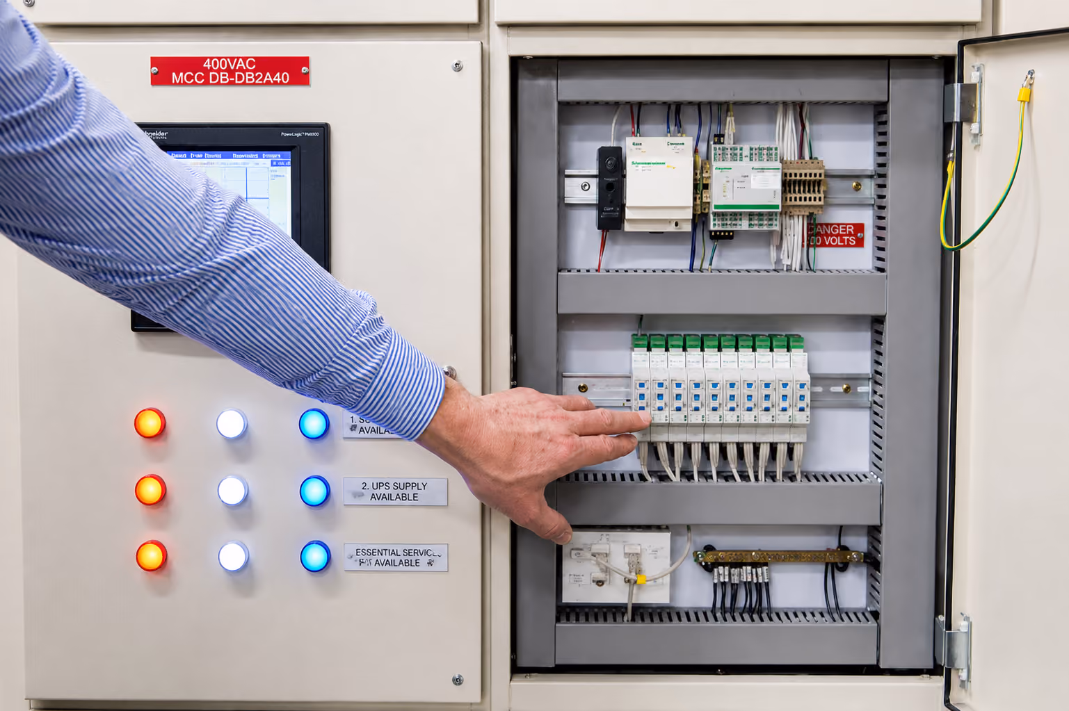 Hand adjusting switches on an open industrial electrical control board with indicator lights on the panel door.
