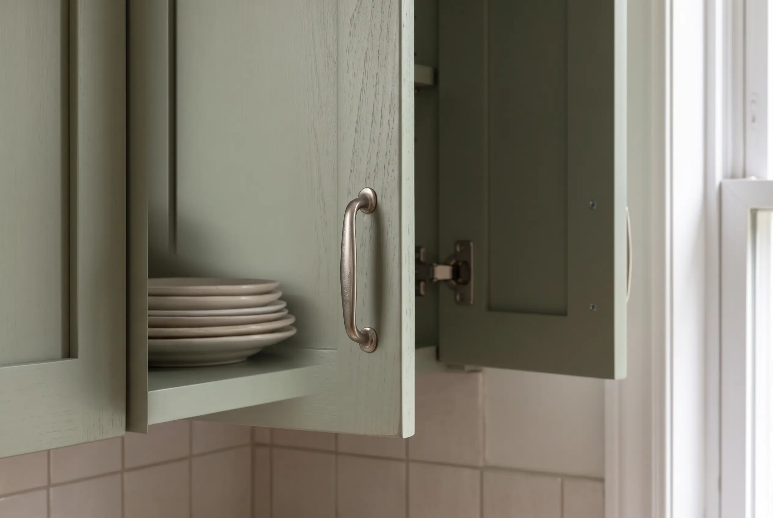 Cabinet design detail showing a sage door, hardware and an interior shelf