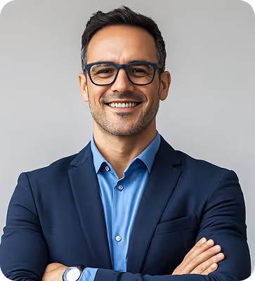 Smiling man wearing glasses, a blue shirt, and a navy blazer with arms crossed.