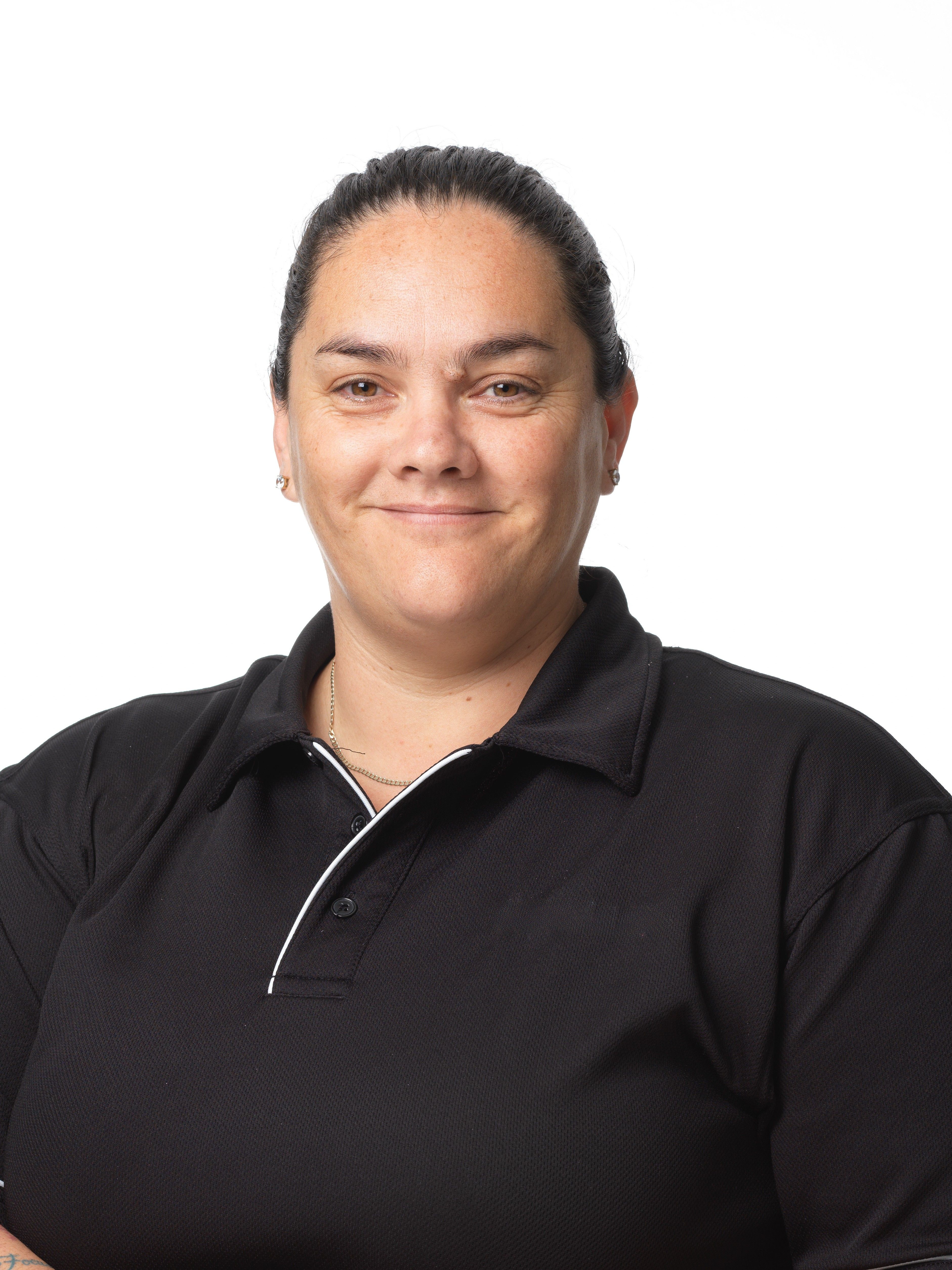 Smiling woman with dark hair pulled back wearing a black collared shirt against a white background.