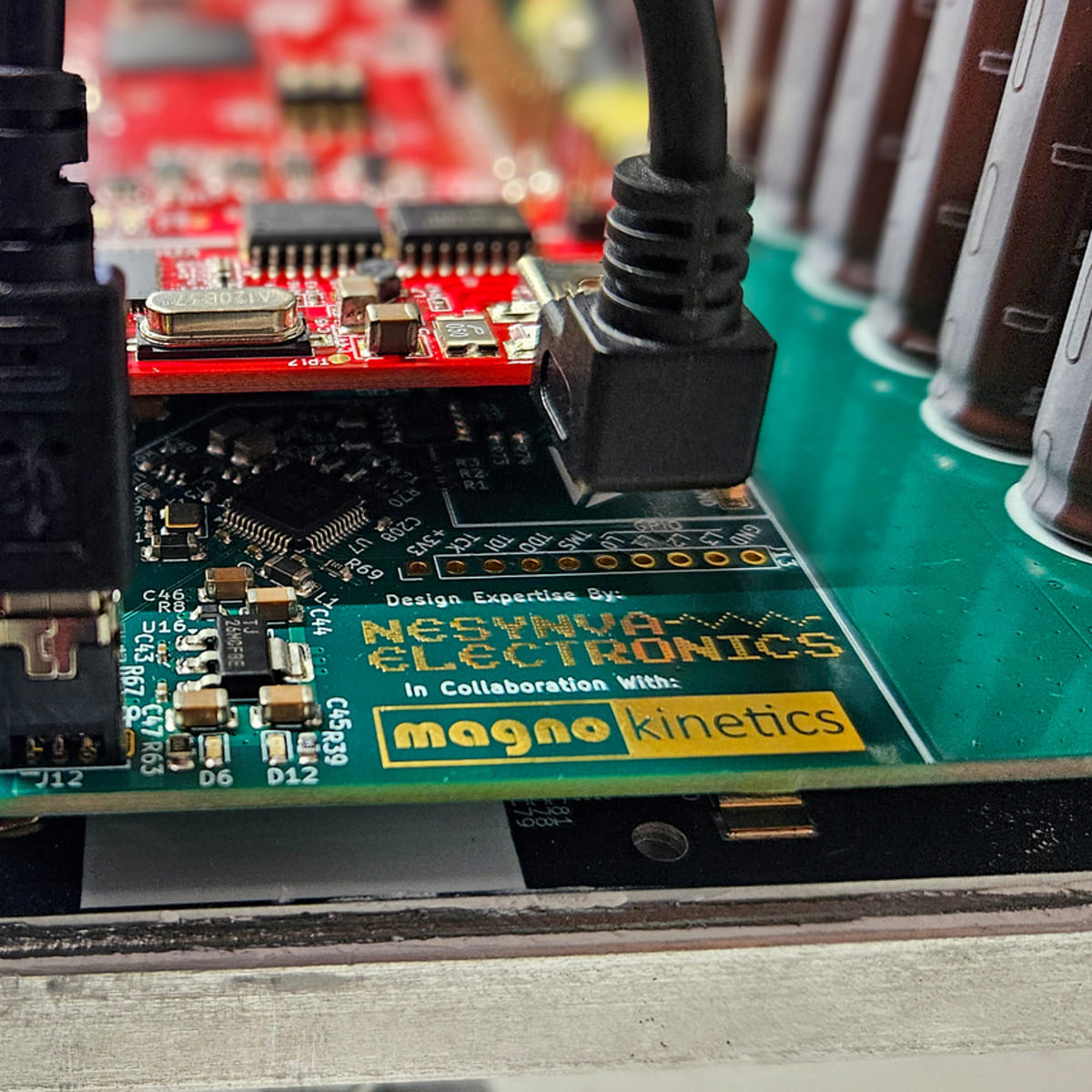 Close-up of an electronic circuit board showing components, connectors, and labels for Nesynva Electronics and magno kinetics.