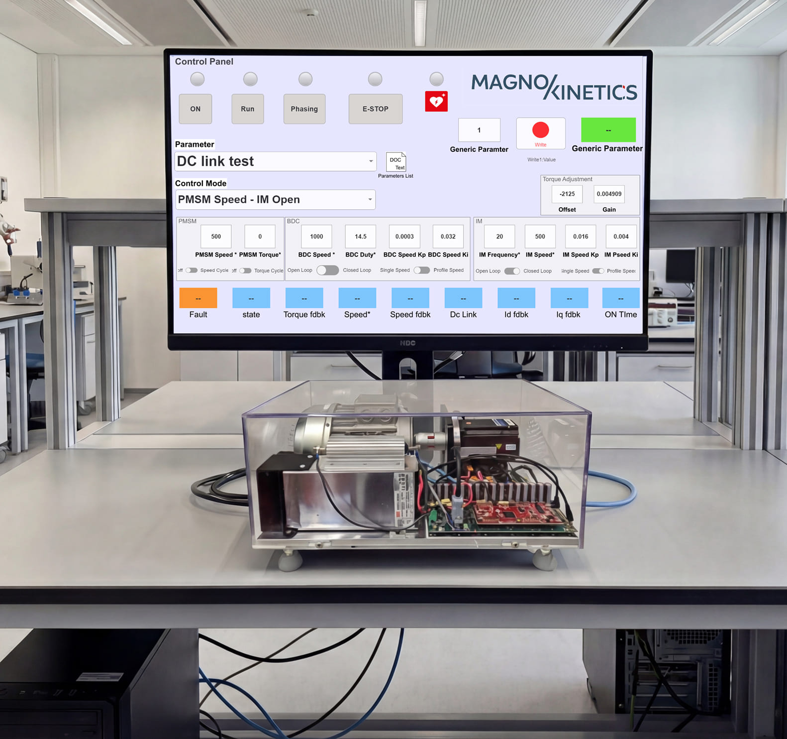 Laboratory setup with a transparent enclosure housing electronic components and a motor, surrounded by multiple oscilloscopes displaying waveform data.