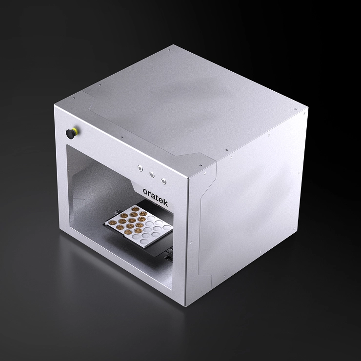 Oratek machine with a tray holding samples, used for scientific or medical analysis.