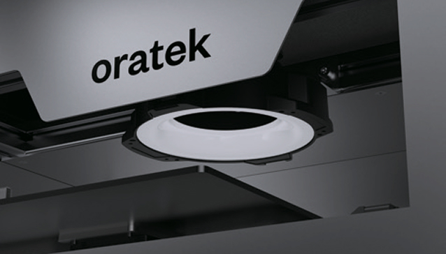 Close-up of a white Oratek branded industrial or laboratory device with a circular light or lens.