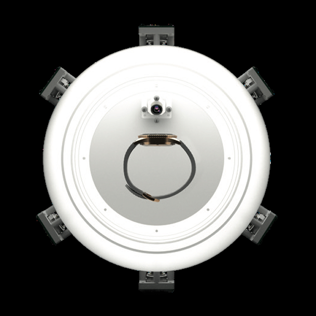Top-down view of a wristwatch inside a circular white ring light with multiple mounted cameras around it.
