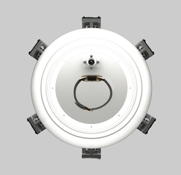 Top view of a round white device with a camera and a black wristband inside, set against a gray background.