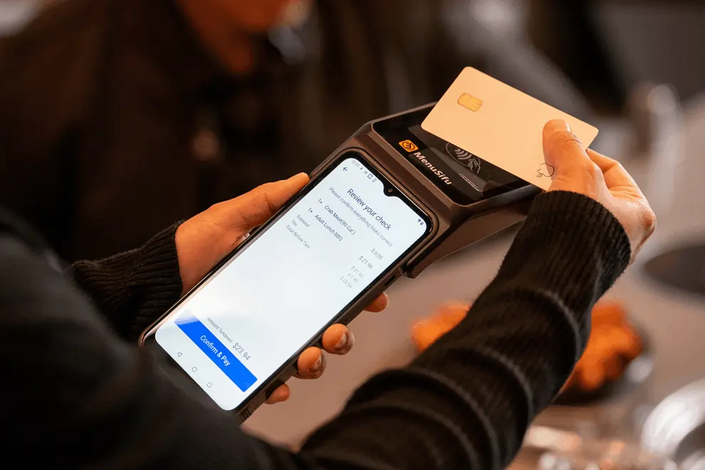 Tap-to-pay credit card transaction in progress on handheld POS showing review screen with $23.94 due and clear payment prompt.