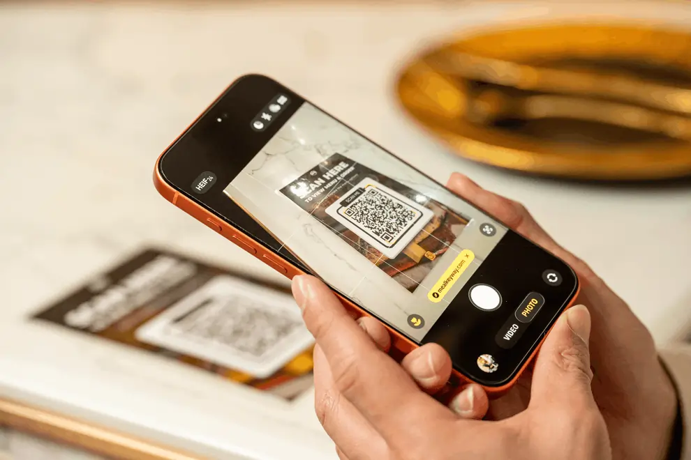 Person scanning a QR code with a smartphone to access a digital menu at a restaurant.