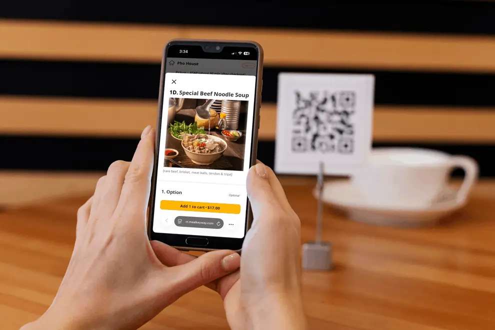 Guest using smartphone to order food after scanning QR code at a restaurant table.