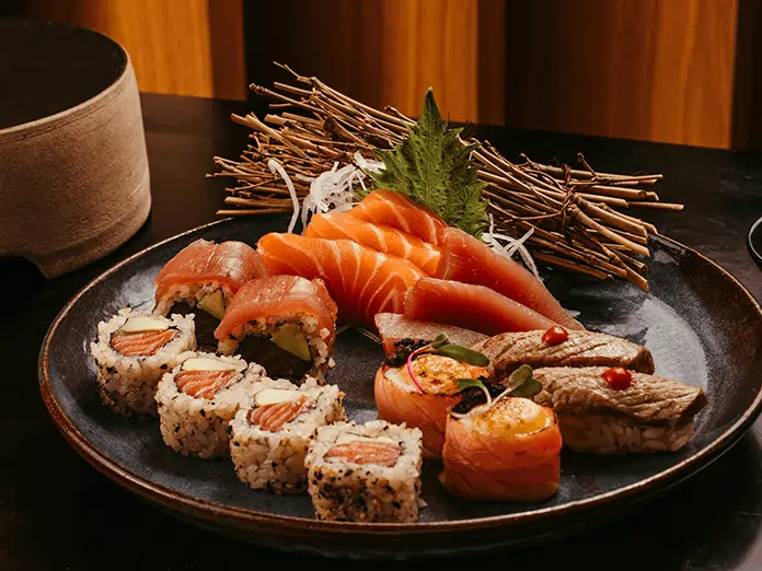 Sushi Restaurant dish showcasing a variety of sushi rolls, fresh sashimi, and seared nigiri with leaf and twig garnish.