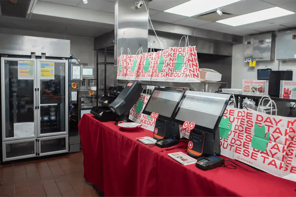 Nice Day restaurant kitchen setup with Hestia robot system, takeaway bags, and touchscreen POS for streamlined operations.