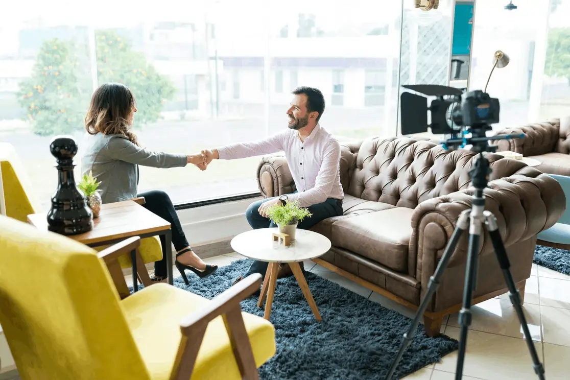 Man and woman shaking hands in a filmed interview setup, illustrating WEFOOD’s premium media access for brand visibility.