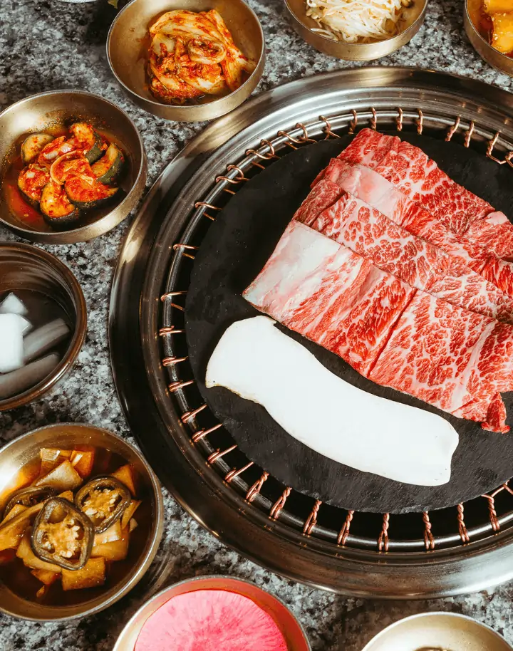 Korean BBQ grill with meat and sides ordered using POS system for Korean restaurants