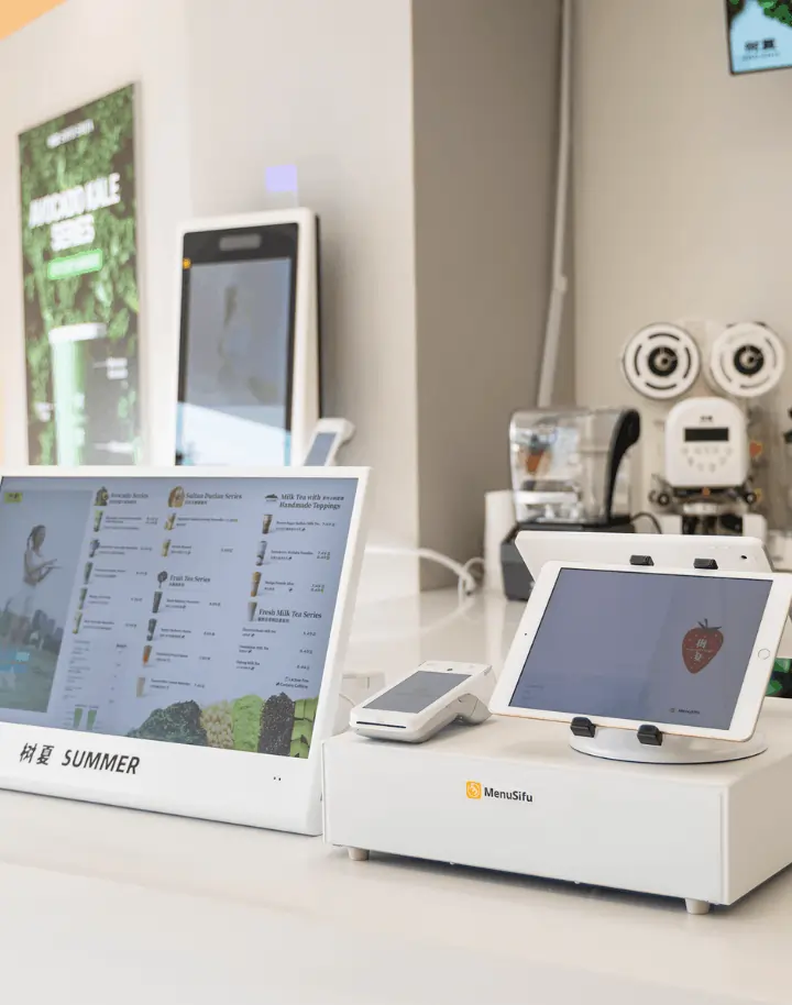 Quick-service restaurant counter featuring Menusifu POS system with tablet ordering and digital menu display screens.