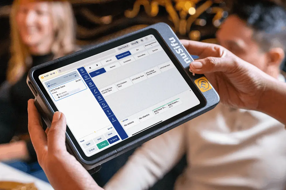 Handheld POS tablet screen showing itemized taco order and add-ons, used by server during live table-side order entry.