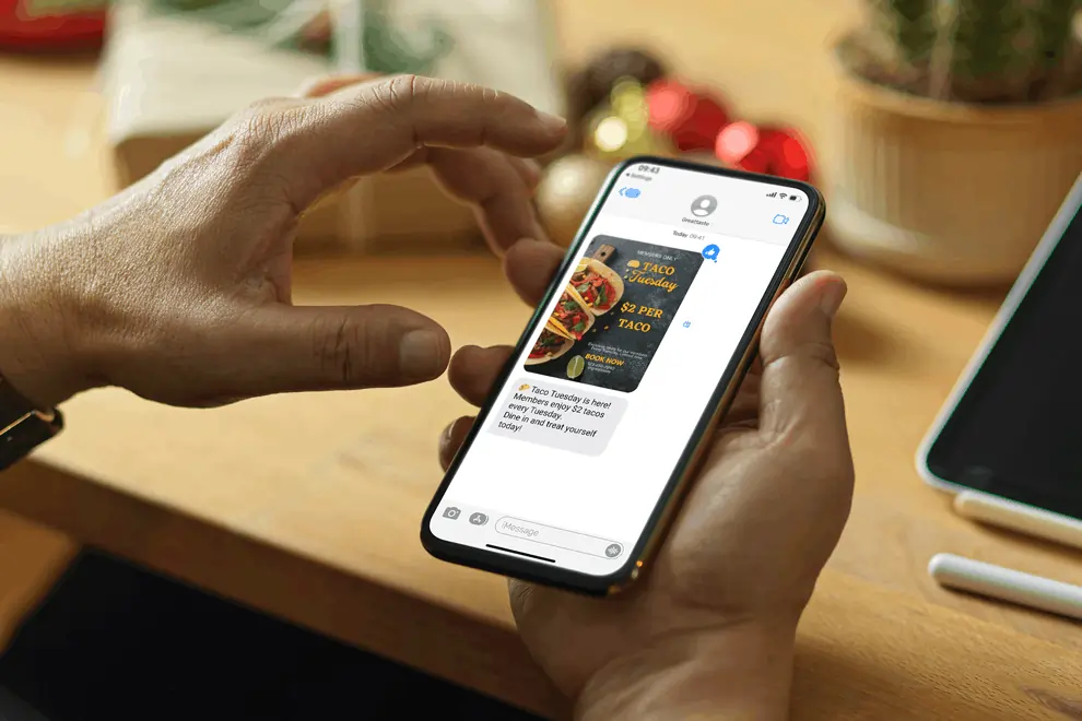 The phone displays a Mexican restaurant's SMS promotion for $2 tacos on Taco Tuesday.