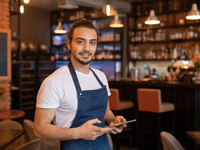 Server in apron holds tablet while managing orders efficiently with a modern Mexican restaurant POS system.