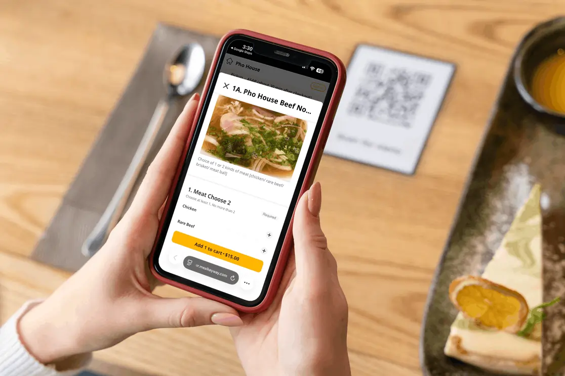 Customer places a QR order for pho on a smartphone at a restaurant tabletop with menu details and add-to-cart options visible.