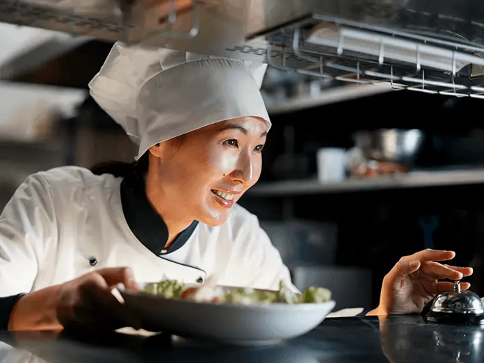Chef plates fresh dish in kitchen, highlighting efficiency and service control powered by a full service restaurant pos system.