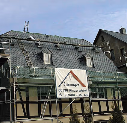 Haus mit Schieferdach in Renovierung, Gerüst und Schild mit der Aufschrift 'Schwager 08396 Niederwinkel' und Telefonnummer.