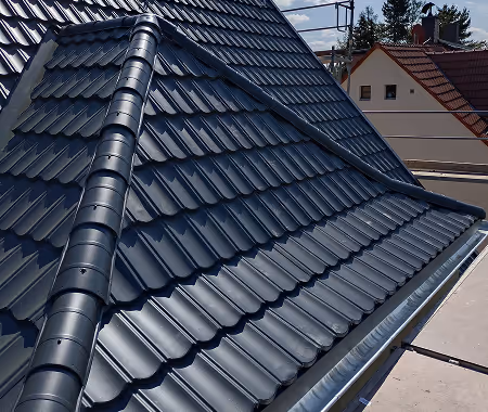 Nahaufnahme eines Daches mit glänzenden schwarzen Dachziegeln an einem sonnigen Tag.