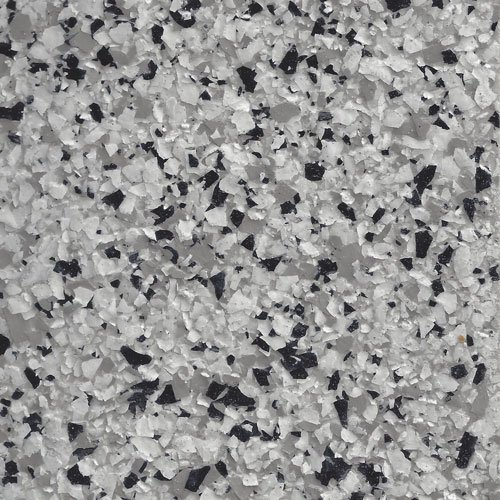 Close-up of a textured epoxy floor coating with white, gray, and black flakes scattered on a gray base.