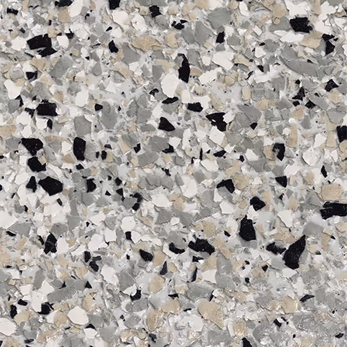 Close-up of epoxy floor coating with a mix of black, gray, white, and beige flakes scattered on a light gray base.