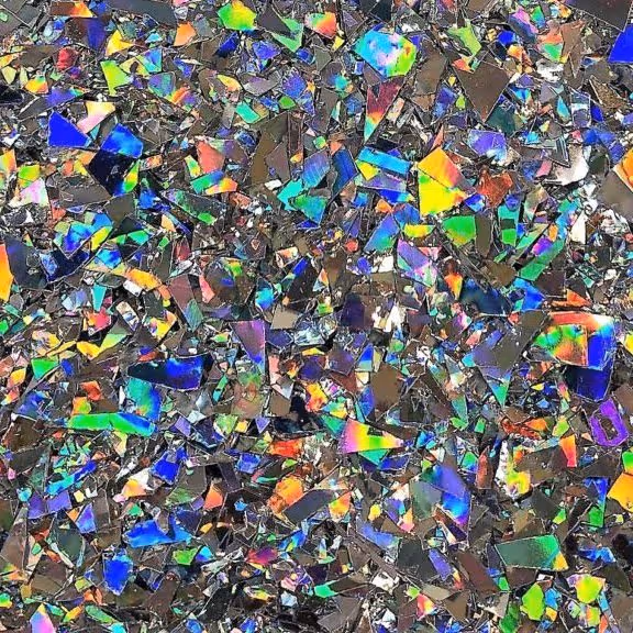 Close-up of multicolored holographic flakes reflecting light in various rainbow hues.