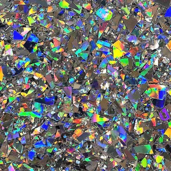 Close-up of multicolored holographic flakes reflecting light in various rainbow hues.