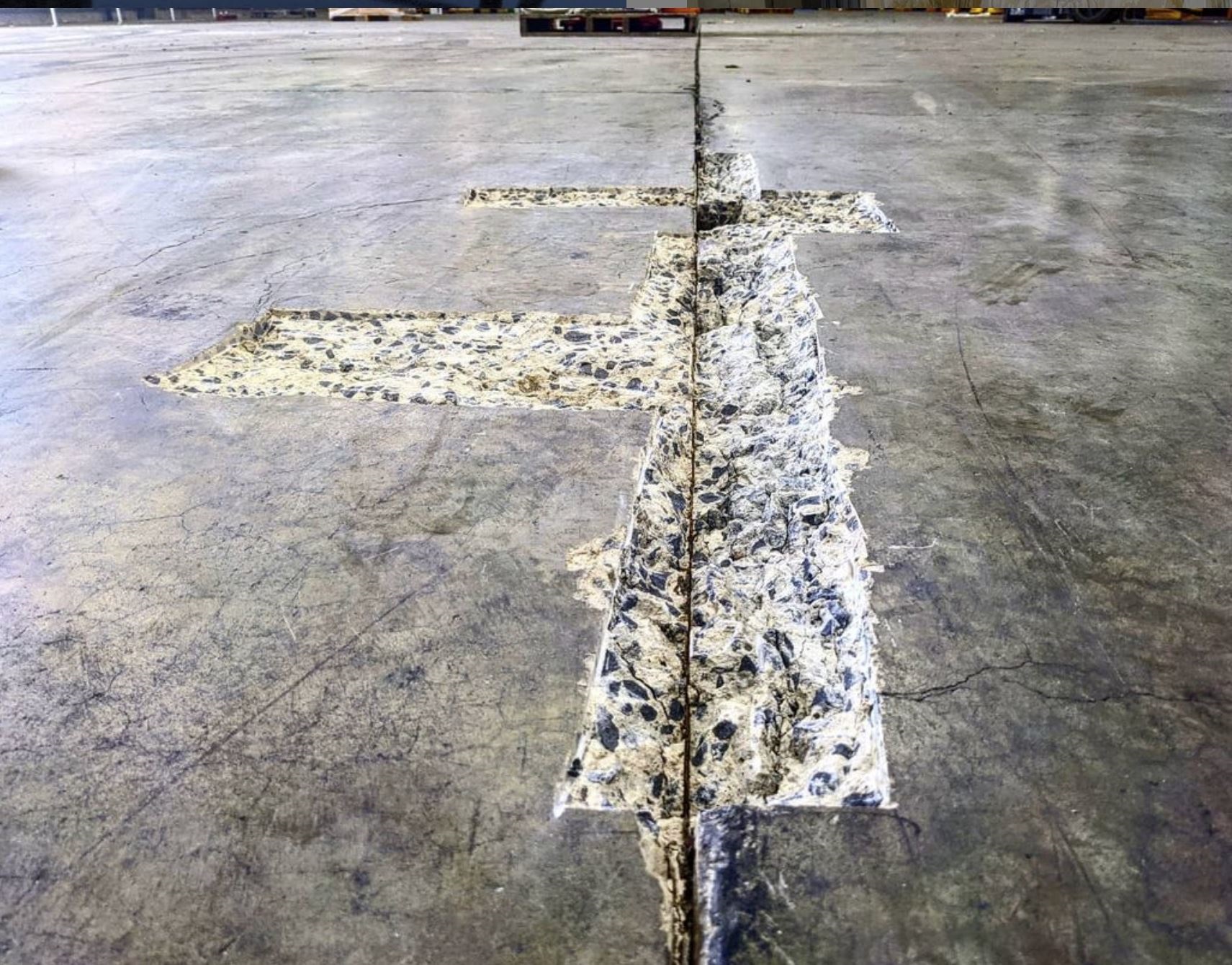 Close-up of a concrete floor with an exposed section showing aggregate beneath the surface along a crack.