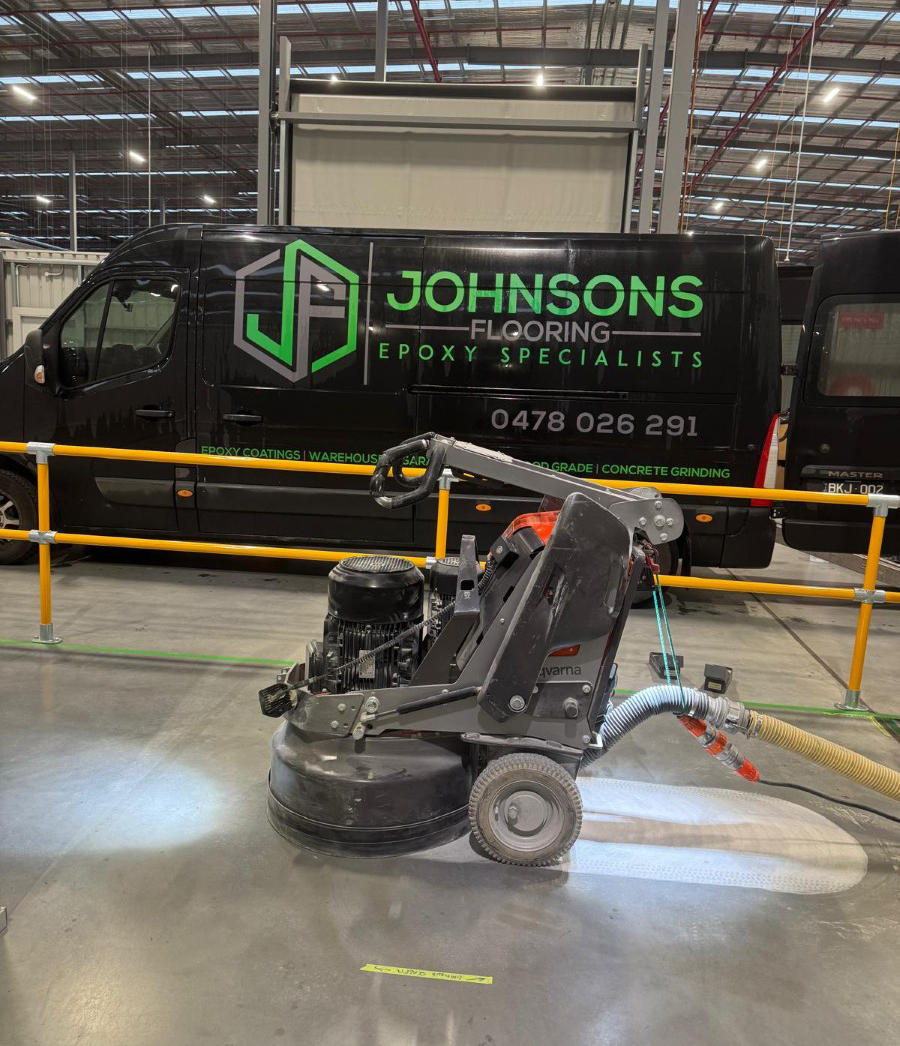 Concrete grinding in a Melbourne warehouse with Johnsons Flooring van in the background.