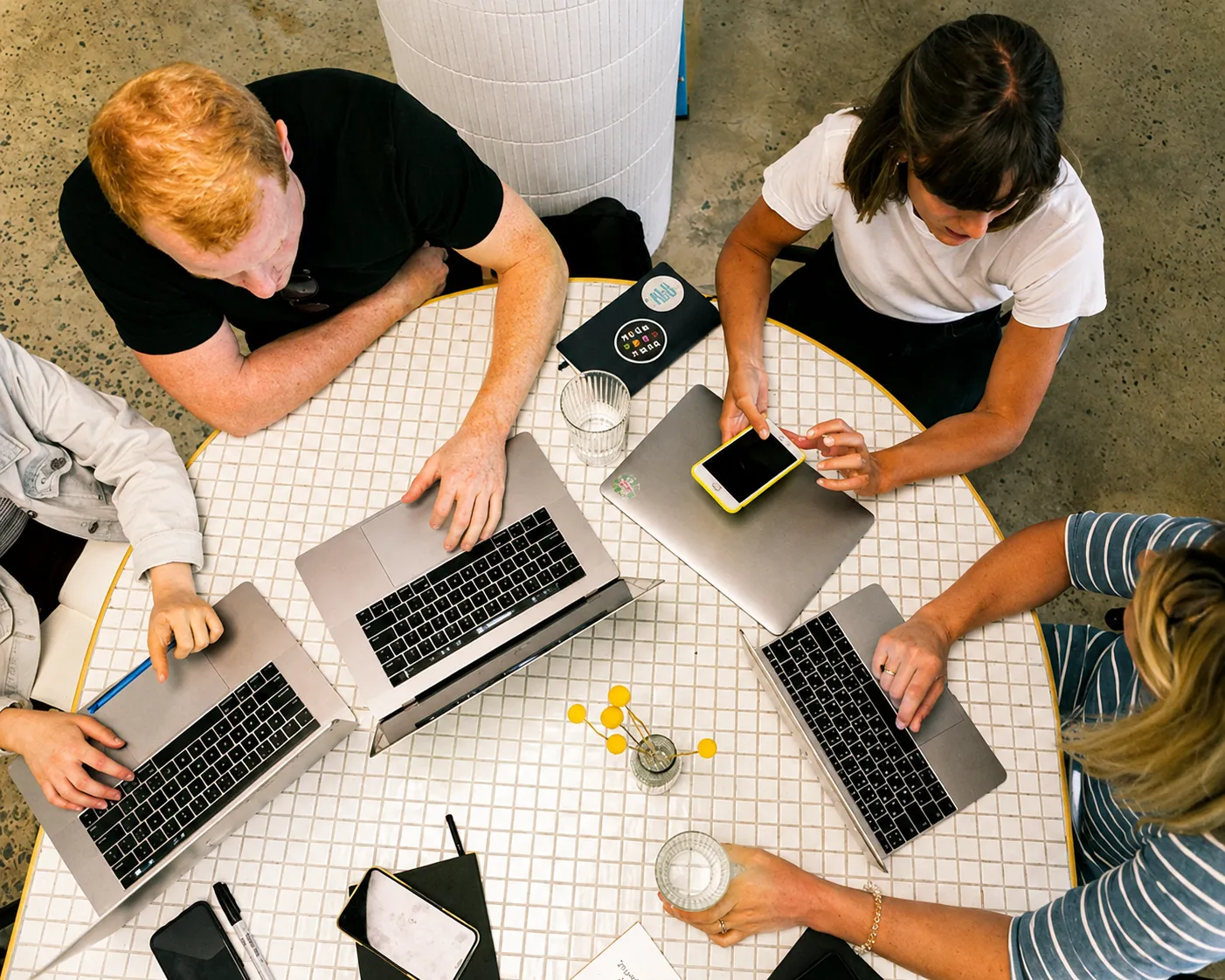 Person working on a laptop displaying code with a smartphone and coffee cup on a round table.