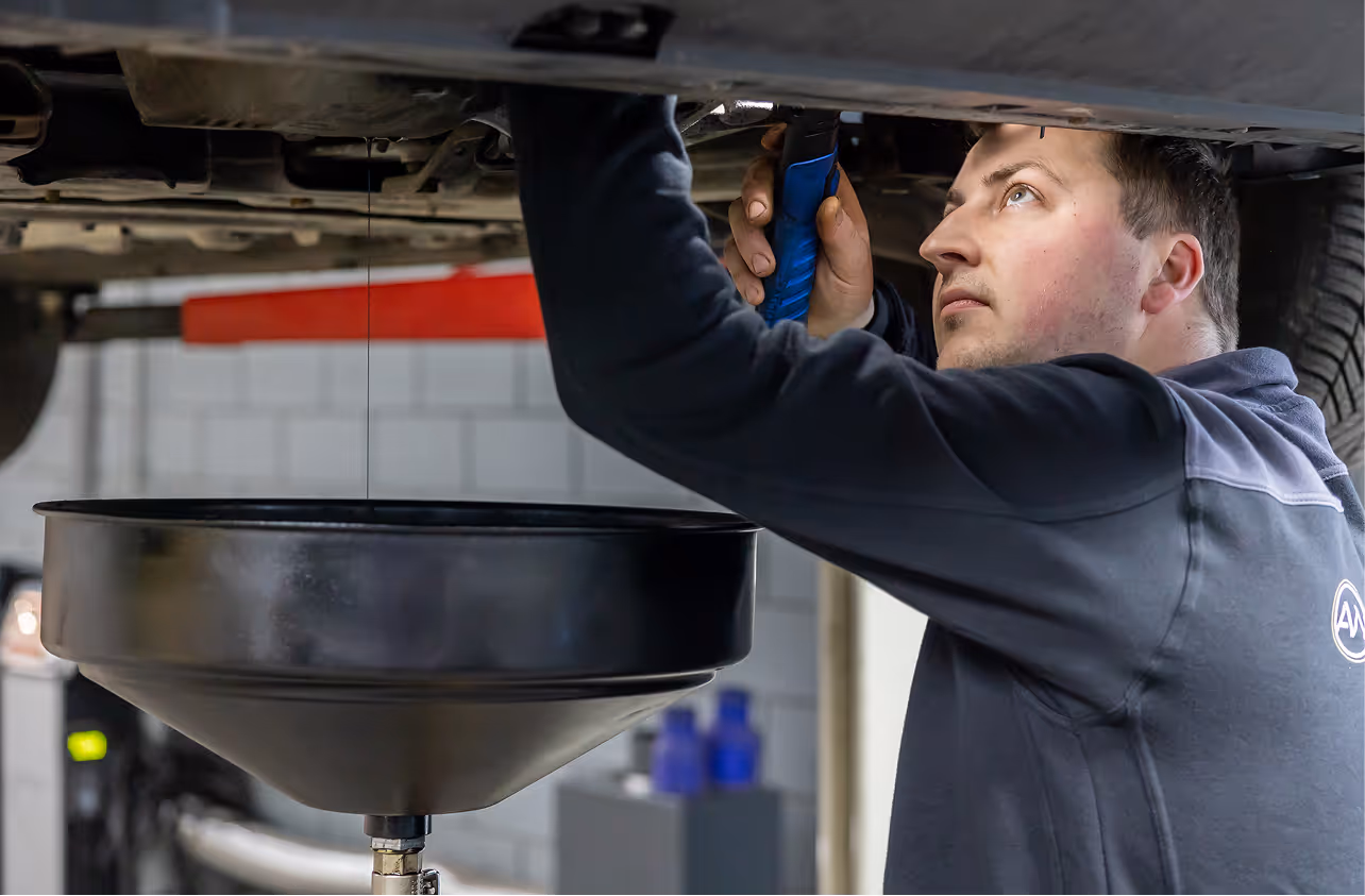 Een monteur controleert de onderkant van een auto tijdens de APK keuring